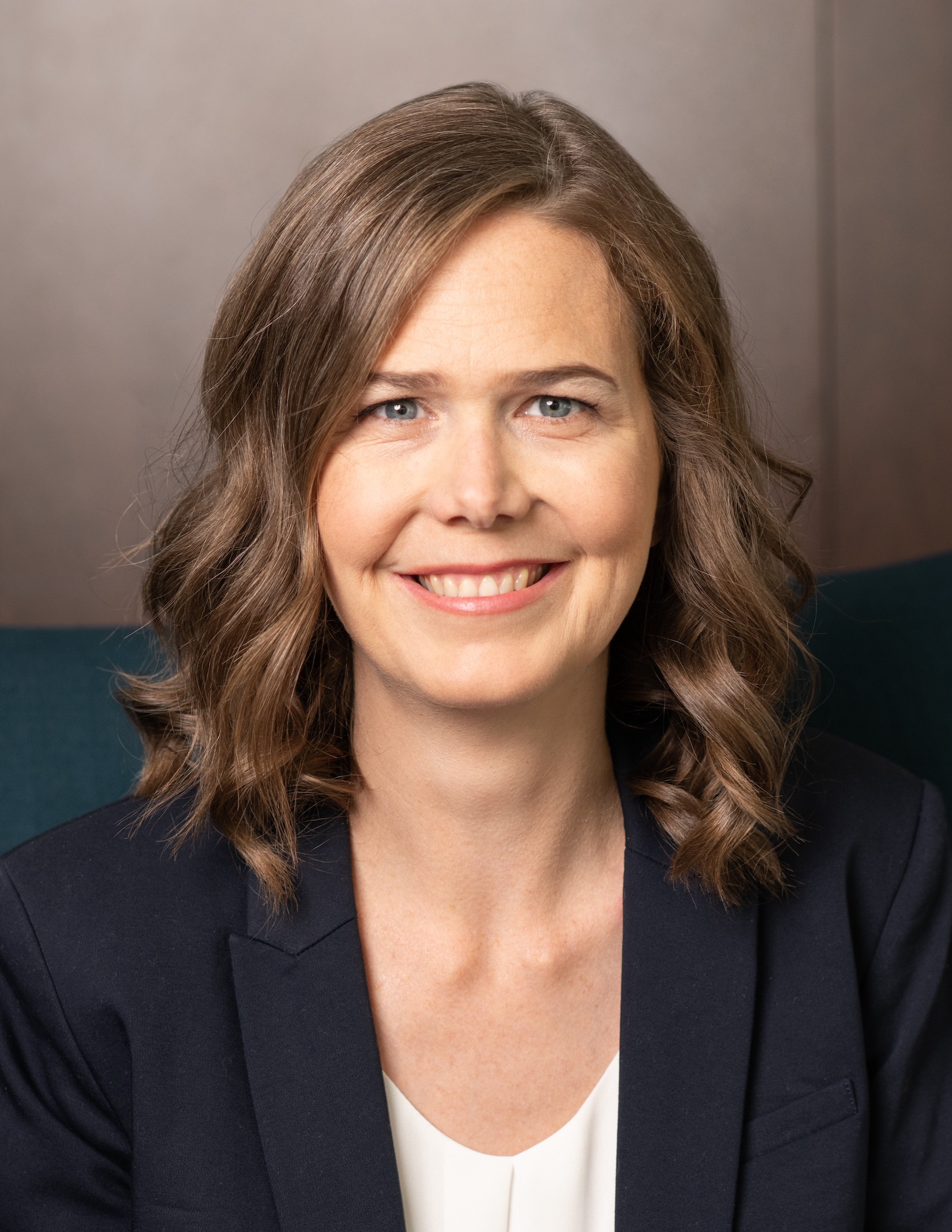 Professional headshot of Deborah Seabrook, who is wearing a white shirt under a dark blazer and has shoulder-length light brown hair.